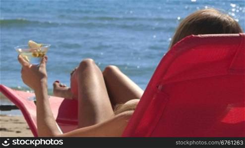 Woman with cocktail relaxing on summer beach resort rear view