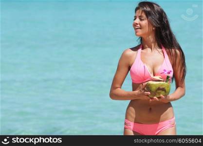 Woman with coconut cocktail on beach. Beautiful smiling young woman in bikini with coconut cocktail on beach