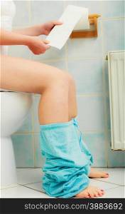 Woman with constipation or diarrhoea sitting on toilet with her blue pajamas down around her legs