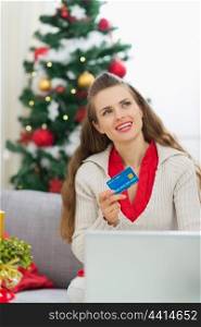 Woman with credit card thinking about Christmas presents