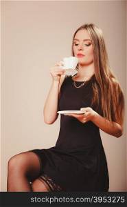 Woman with cup of coffee. Break and relax time. Elegant beauty woman in black dress holding and drinking hot fresh coffee in white heart shaped cup mug.