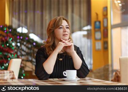 Woman with cup of coffee in restaurant