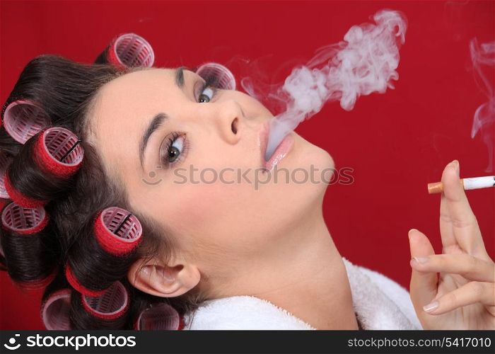 woman with curlers in her hair smoking