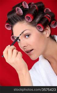 Woman with curlers putting on makeup