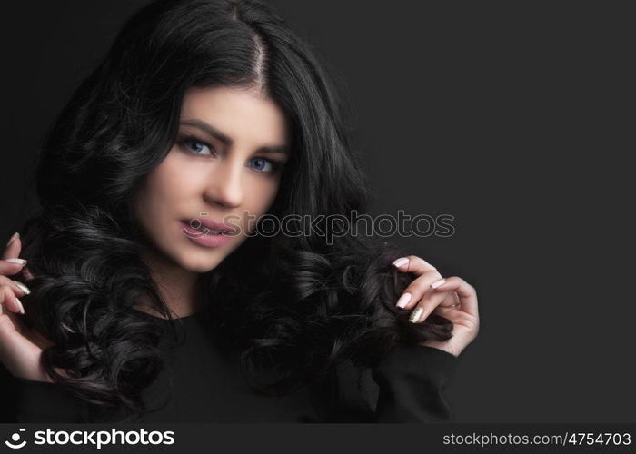 Woman with curly hair. Beautiful woman holding her dark curly hair