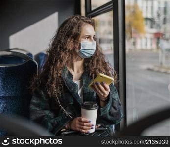 woman with curly hair holding mobile phone coffee