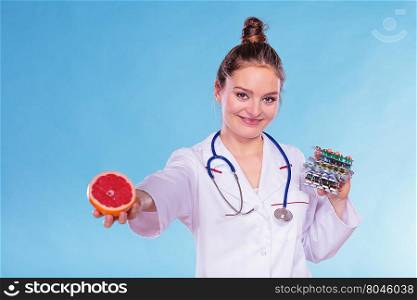 Woman with diet weight loss pills and grapefruit.. Dietitian nutritionist woman holding diet weight loss tablets pills and grapefruit. Choice between natural and synthetic way of slimming dieting. Health care.