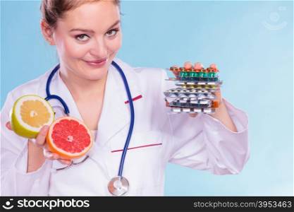 Woman with diet weight loss pills and grapefruits.. Dietitian nutritionist woman holding diet weight loss tablets pills and grapefruits. Choice between natural and synthetic way of slimming dieting. Health care.