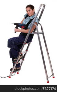 Woman with drill sitting on metal staircase