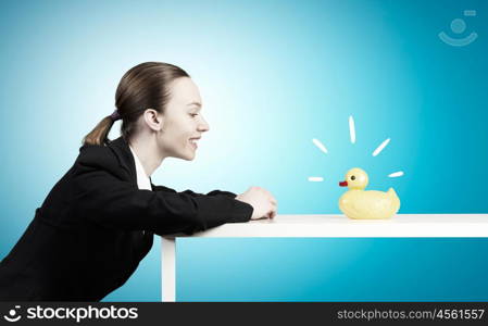 Woman with duck toy. Young businesswoman and yellow rubber duck toy on table