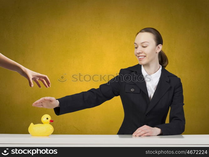 Woman with duck toy. Young businesswoman and yellow rubber duck toy on table