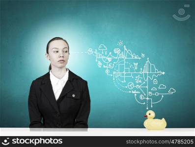 Woman with duck toy. Young businesswoman and yellow rubber duck toy on table