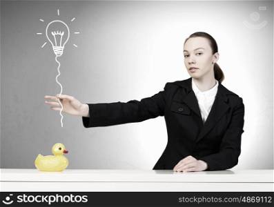 Woman with duck toy. Young businesswoman and yellow rubber duck toy on table
