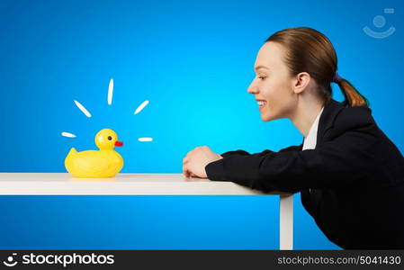 Woman with duck toy. Young businesswoman and yellow rubber duck toy on table