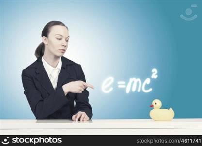 Woman with duck toy. Young businesswoman pointing with finger at yellow rubber duck toy on table