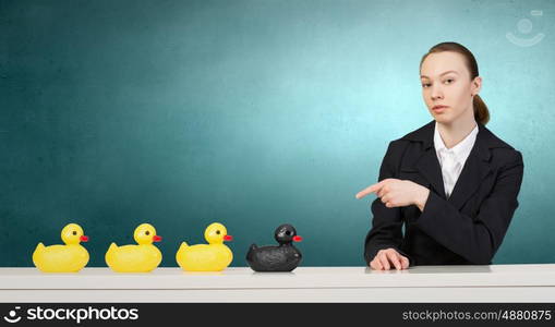 Woman with duck toy. Young businesswoman pointing with finger at yellow rubber duck toy on table