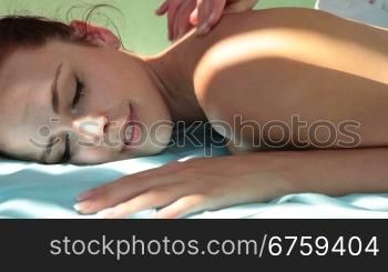 Woman with eyes closed receiving massage therapy at spa resort.