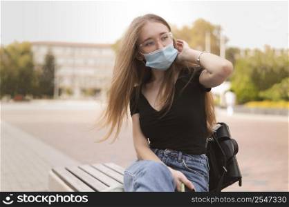 woman with face mask sitting bench