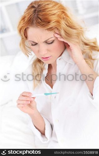 Woman with fever looking at thermometer