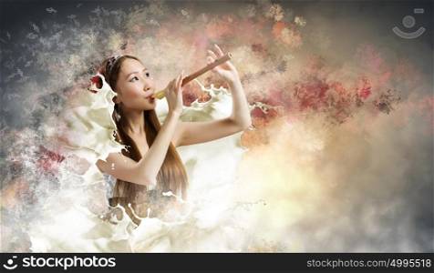 Woman with fife. Young asian woman against colorful background playing fife