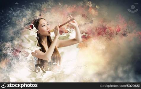 Woman with fife. Young asian woman against colorful background playing fife