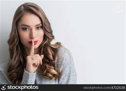 Woman with finger on lips. Portrait of beautiful woman with finger on lips