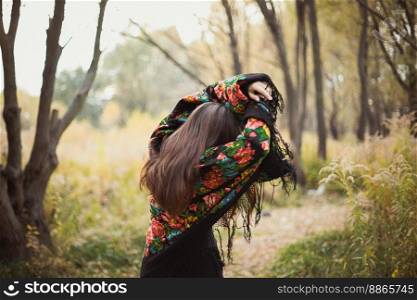 Woman with floral shawl hiding from sunlight scenic photography. Picture of lady with woodland on background. High quality wallpaper. Photo concept for ads, travel blog, magazine, article. Woman with floral shawl hiding from sunlight scenic photography