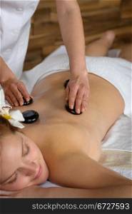 Woman with flower at spa having hot stone back treatment