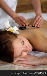Woman with flower at spa having hot stone back treatment