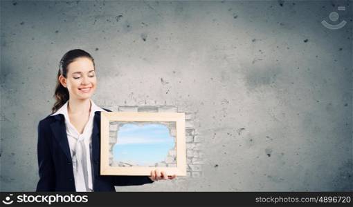 Woman with frame. Young woman holding wooden frame with cloud scape