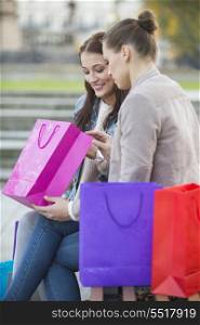 Woman with friend looking into shopping bag outdoors