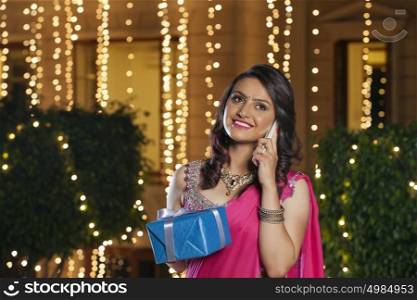 Woman with gift talking on mobile phone