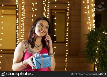 Woman with gift talking on mobile phone