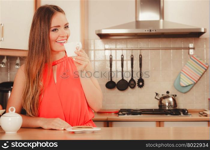 Woman with gingerbread cookies drinking tea coffee. Pretty woman with heart shape gingerbread cookies drinking tea or coffee at home. Gorgeous young girl with hot beverage relaxing in kitchen.