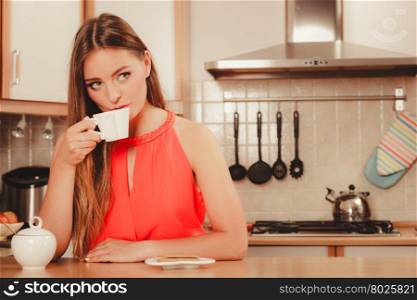 Woman with gingerbread cookies drinking tea coffee. Pretty woman with heart shape gingerbread cookies drinking tea or coffee at home. Gorgeous young girl with hot beverage relaxing in kitchen.