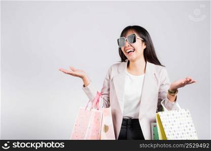 Woman with glasses confident shopper smiling holding online shopping bags colorful multicolor, Portrait excited happy Asian young female person studio shot isolated on white background, fashion sale