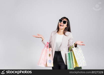 Woman with glasses confident shopper smiling holding online shopping bags colorful multicolor, Portrait excited happy Asian young female person studio shot isolated on white background, fashion sale