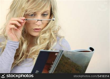 Woman with glasses reading magazine