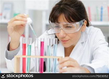 woman with glasses works with liquid pipette
