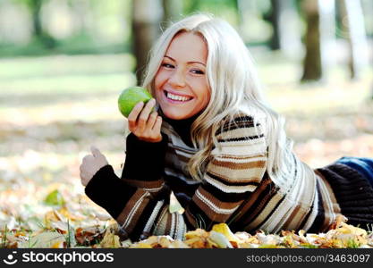 woman with green apple in autumn park