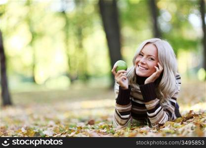 woman with green apple in autumn park
