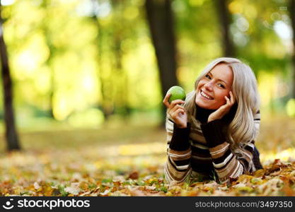 woman with green apple in autumn park