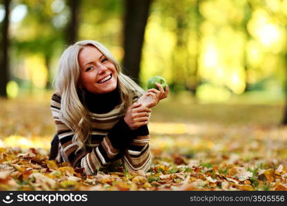 woman with green apple in autumn park