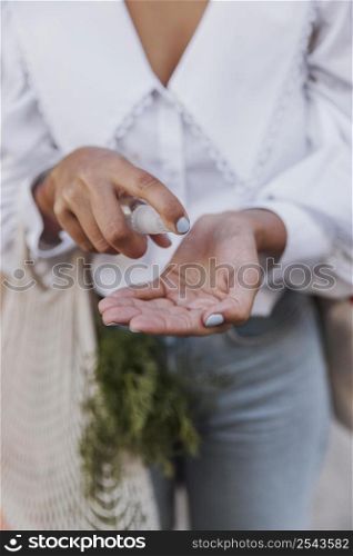 woman with grocery bags using hand sanitizer