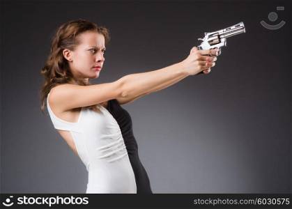 Woman with gun against dark background