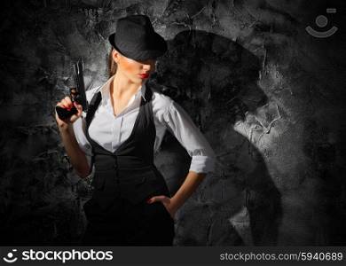 Woman with gun on grey wall background
