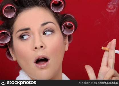 Woman with hair curlers smoking a cigarette
