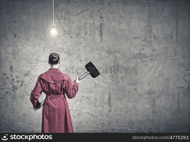 Woman with hammer. Rear view of woman in red coat with hammer in hands