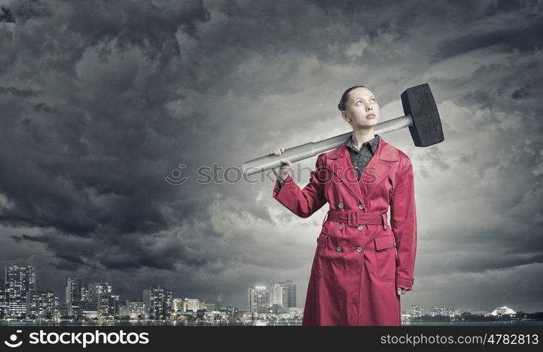 Woman with hammer. Rear view of woman in red coat with hammer in hands