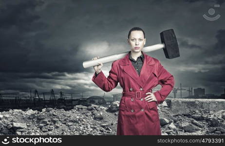 Woman with hammer. Rear view of woman in red coat with hammer in hands